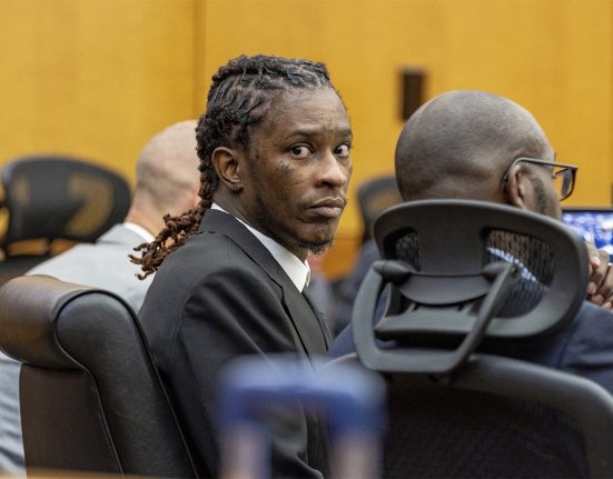 Young Thug faces a camera during his trial in a courtroom.